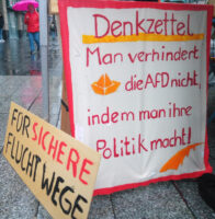 Plakate mit der Aufschrift "Man verhindert die Politik der Afd nicht, indem man ihre Politik macht!" und "Für sichere Fluchtwege"